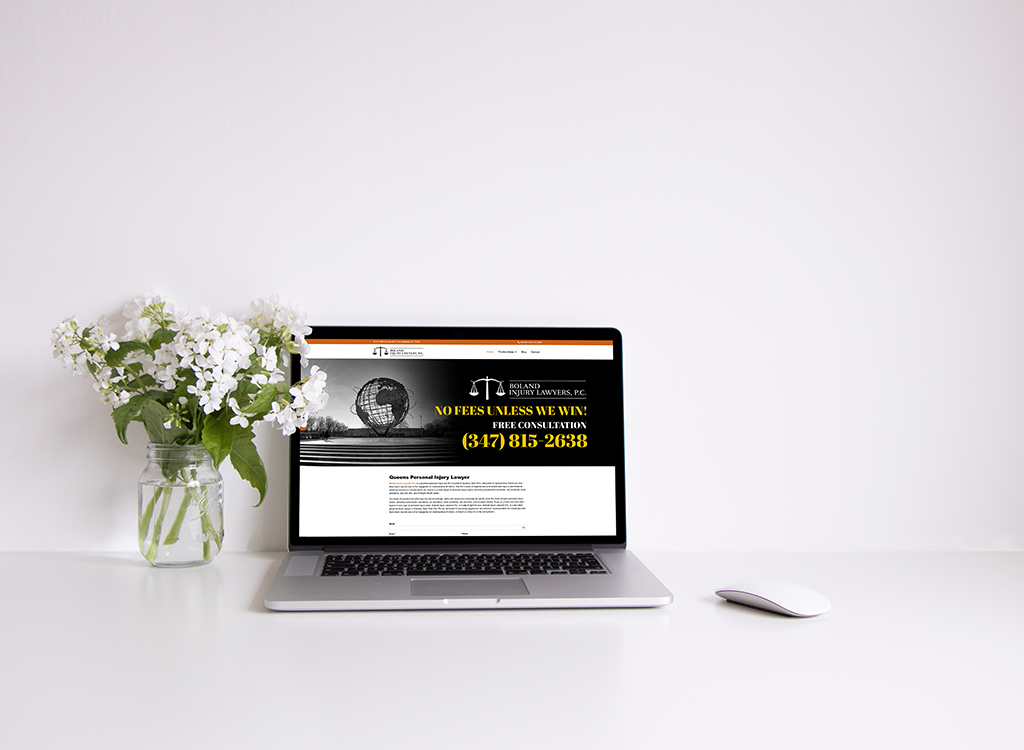 A laptop displaying a personal injury law firm's website, featuring a contact number and a message about free consultations, placed on a clean desk alongside a vase of white flowers.