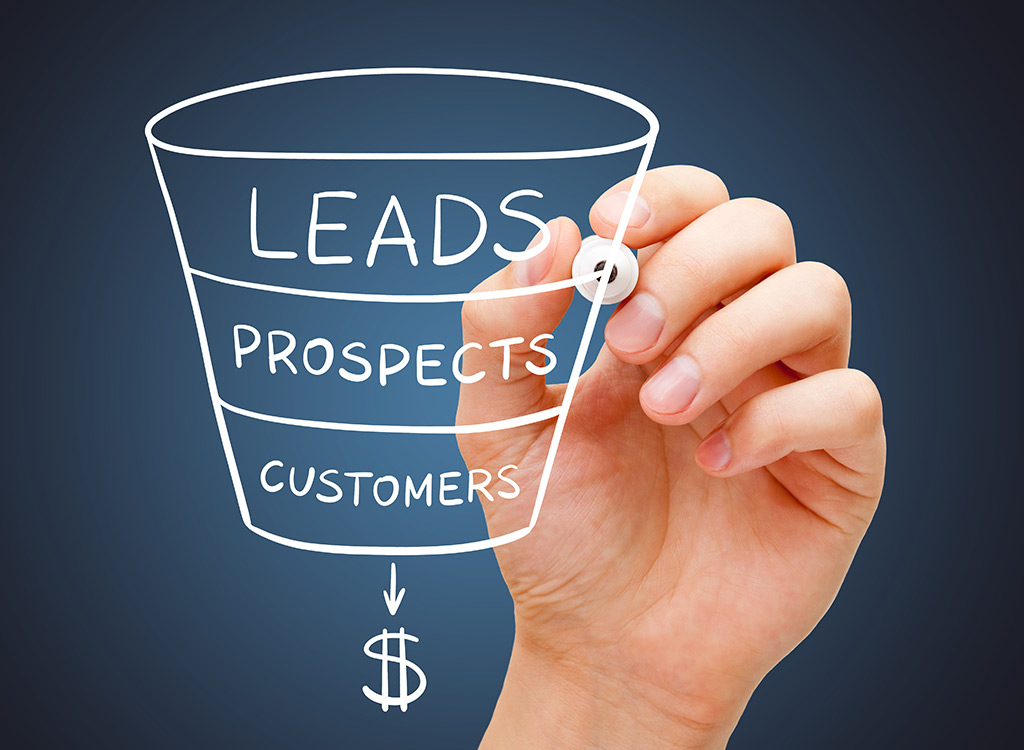 Hand drawing a marketing funnel diagram with the words "Leads," "Prospects," and "Customers," illustrating the sales process leading to revenue, against a dark background.